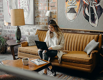 woman sitting on a couch on a computer
